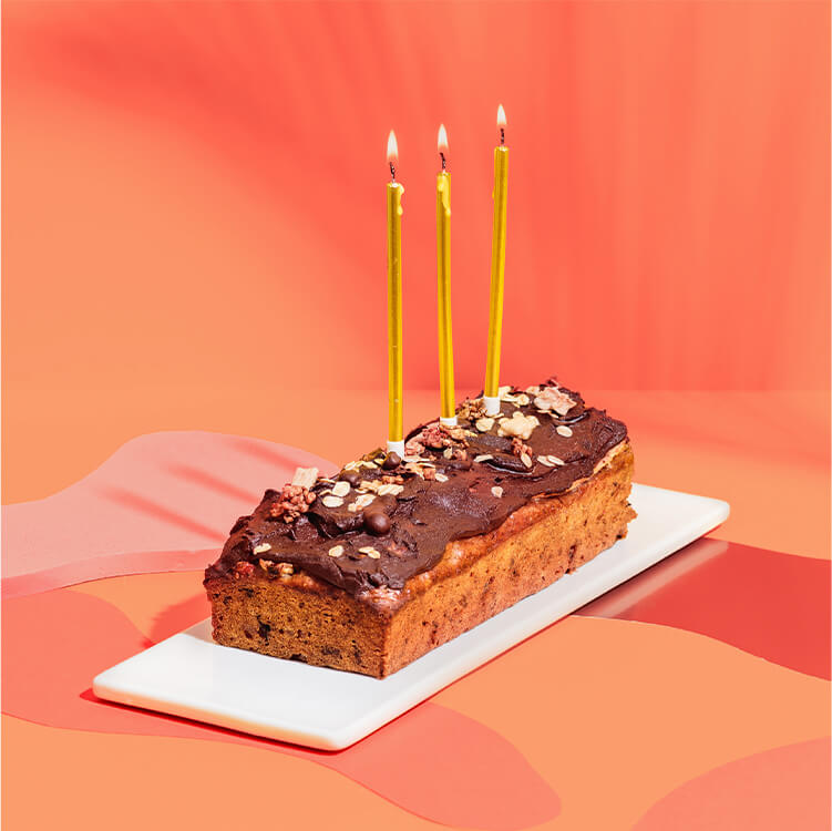 Bananenbrot auf einem Teller mit Kerzen und Konfetti