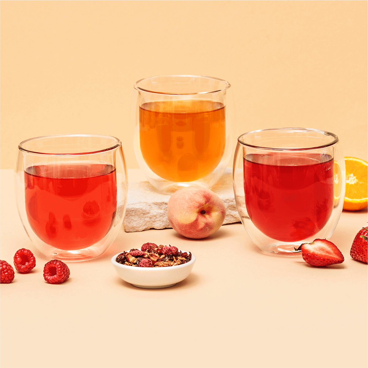 Tree of Tea Früchtetee Set in 3 Teegäsern neben frischem Obst und getrockneten Tee in Schalen
