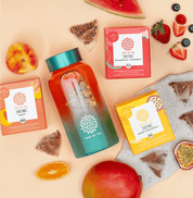 Tree of Tea Ice Tea Starter Set mit einer aufgefüllten Ice Tea bottle in Türkis. Drumherum liegen die enthaltenen Ice Tea Sorten mit frisch aufgeschnittenen Erdbeeren, Wassermelone, Pfirsich, Mango und Passionsfrucht.