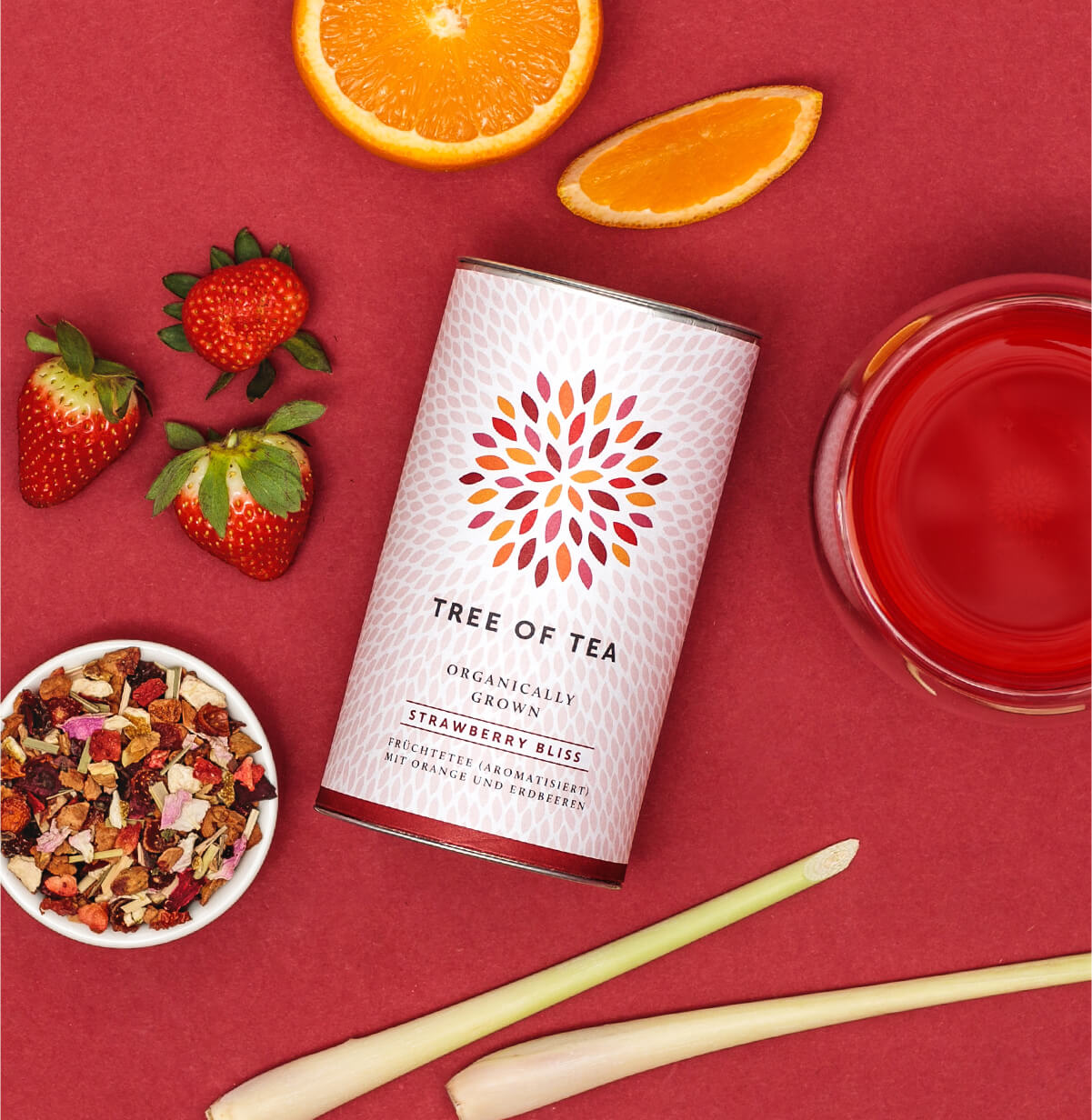 Tree of Tea Strawberry Bliss Früchtetee und daneben ein Glas Tee und Erdbeeren