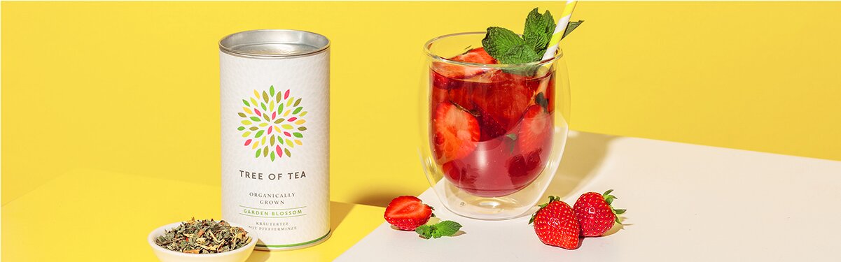 Erdbeer-Minz Eistee in einem Glas mit Teedose daneben