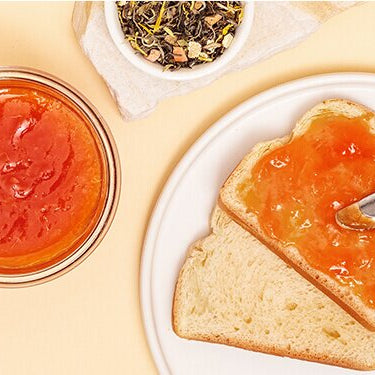 Papaya Orangen Marmelade auf einem Brot mit einer halben Papaya daneben