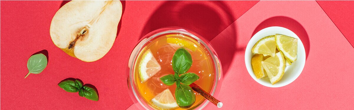 White Tropical Cocktail mit einem halben Apfel und Zitronenstücken daneben