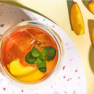 Peachy Bellini in einem Glas und Pfirsiche