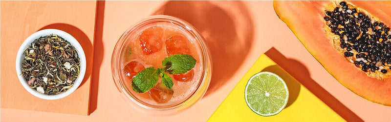 Papaya Eistee mit einer halben Papaya, Limette und Tee daneben