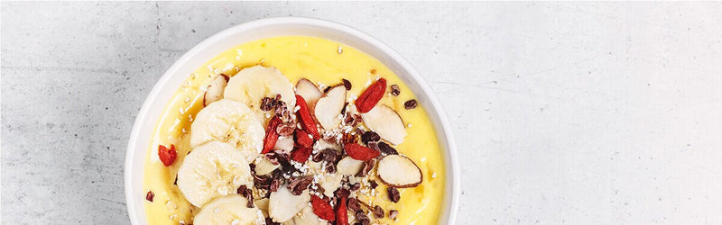 Mango-Kurkuma Bowl in einer Schale mit Bananenscheiben