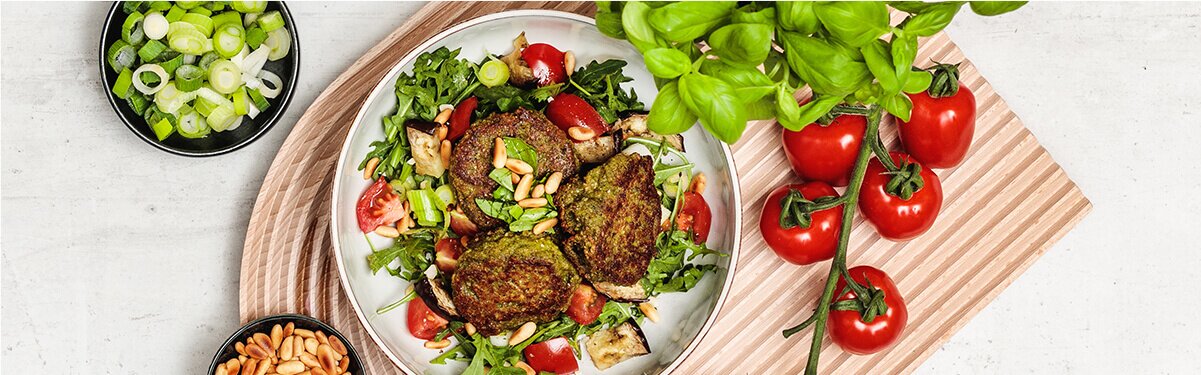 Champignon Mandel Plätzchen auf einem Teller mit Tomaten, Basilikum und Lauchzwiebeln daneben