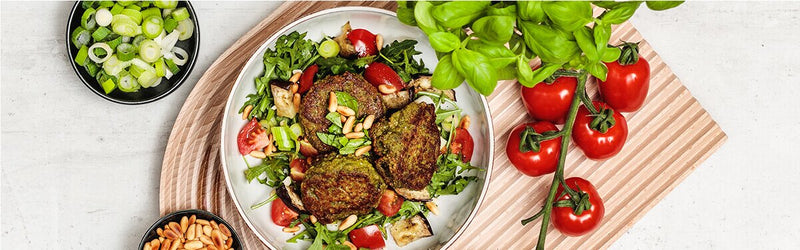 Champignon Mandel Plätzchen auf einem Teller mit Tomaten, Basilikum und Lauchzwiebeln daneben