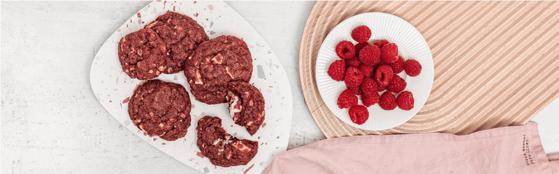 Red Velvet Cookies auf einem Teller und Himbeeren daneben