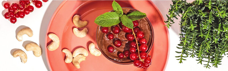 Mousse au Chocolat in einem Glas mit Cashews und Johannisbeeren dekoriert
