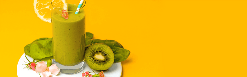 Green Smoothie in einem Glas mit einer halben Kiwi daneben