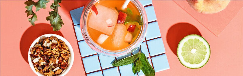 Peach Drink in einem Glas mit Tee und einer halben Limette daneben