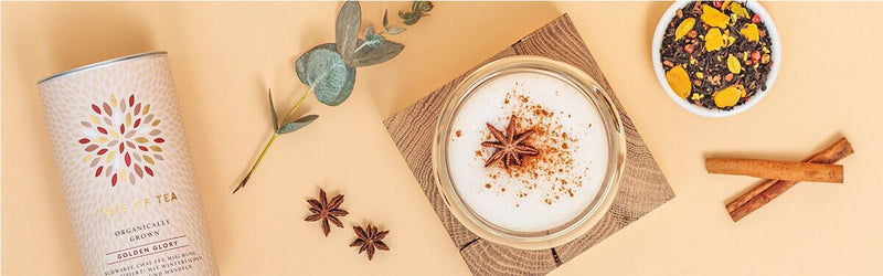Chai Tee Latte mit Tee und Gewürzen daneben