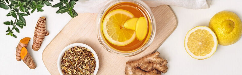 Immunbooster Tee in einem Glas, Zitronen, Ingwer und Kurkuma daneben