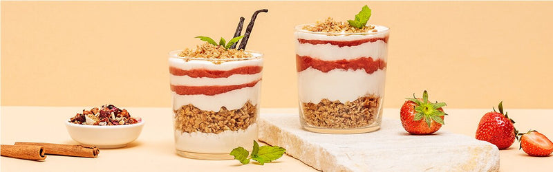 Erdbeer-Schicht-Dessert in einem Glas mit Erdbeeren daneben