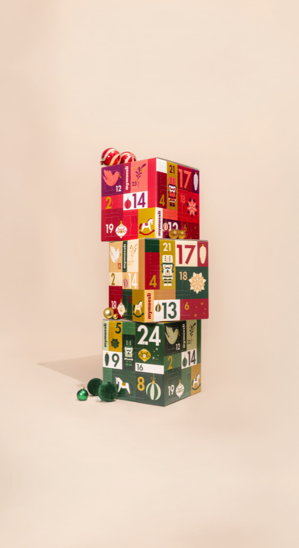 mymuesli Bio Müsli und Porridge Adventskalender, getragen von einer Frau in weihnachtlich grünem Hintergrund.
