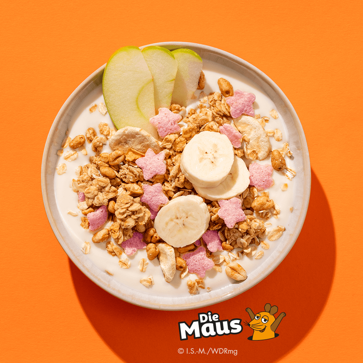 Mymuesli bio Supermaus-Müsli in Schale mit frischen Bananen und frischen Äpfeln von oben.