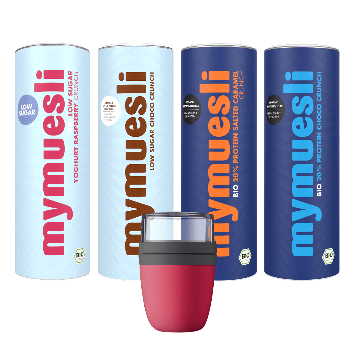Ein mymuesli -Set auf grünem Hintergrund: Zwei hellblaue und zwei dunkelblaue Müslidosen stehen in einer Reihe hinter einem kleinen pinkfarbenen mymuesli Mepal Becher.