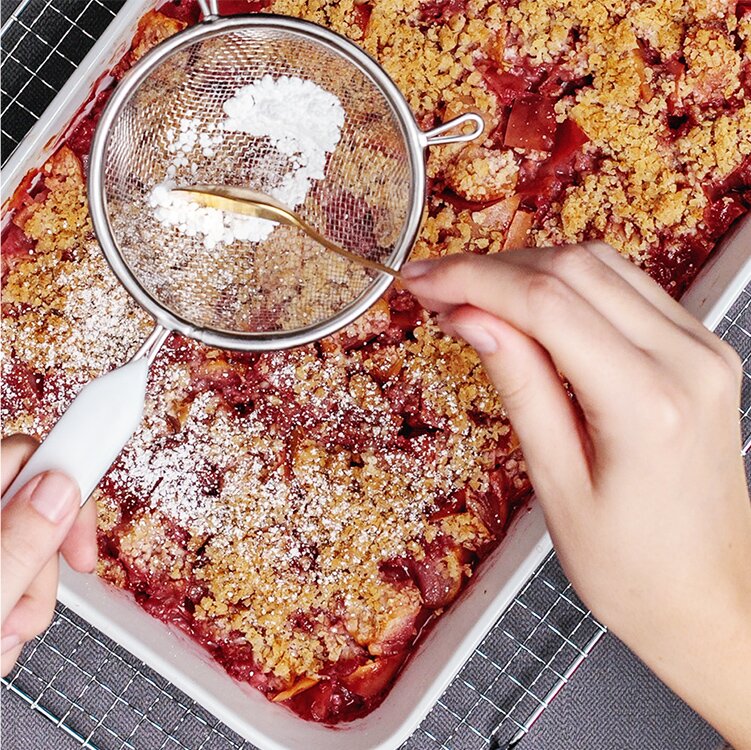Veganer Apple-Crumble in einer Ofenform mit Puderzucker
