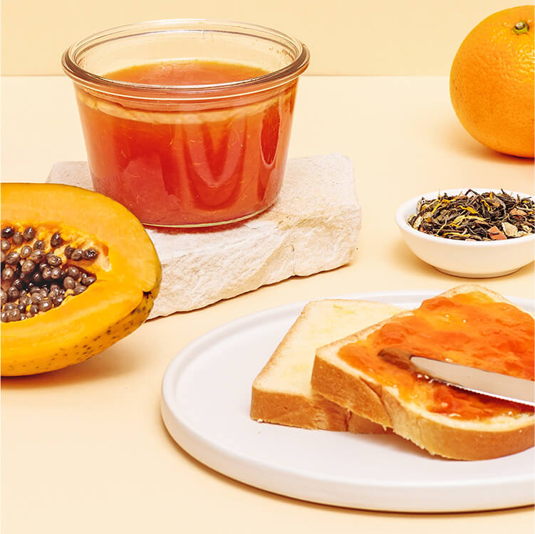 Papaya Orangen Marmelade auf einem Brot mit einer halben Papaya daneben