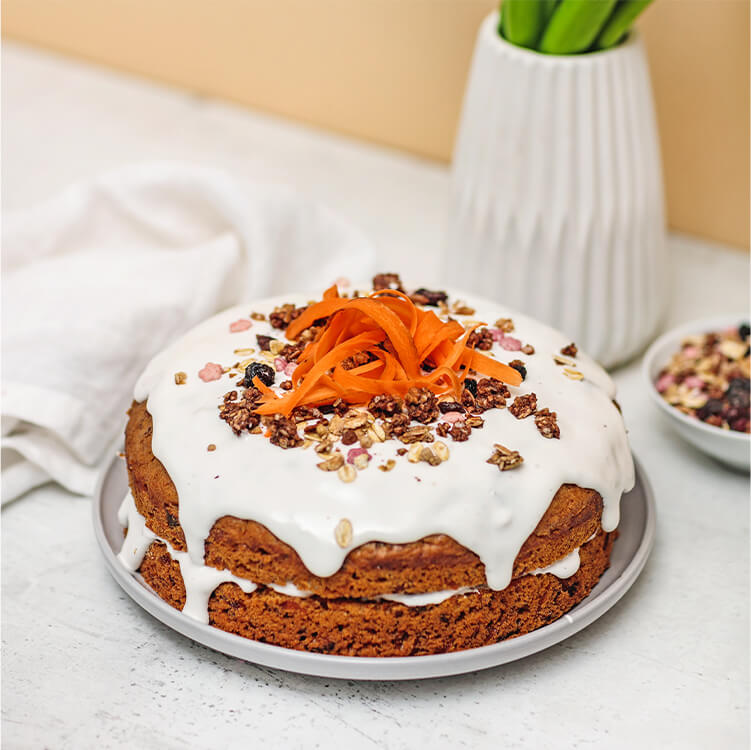 Naked Carrot Cake auf einem Teller, mit geraspelter Möhre dekoriert