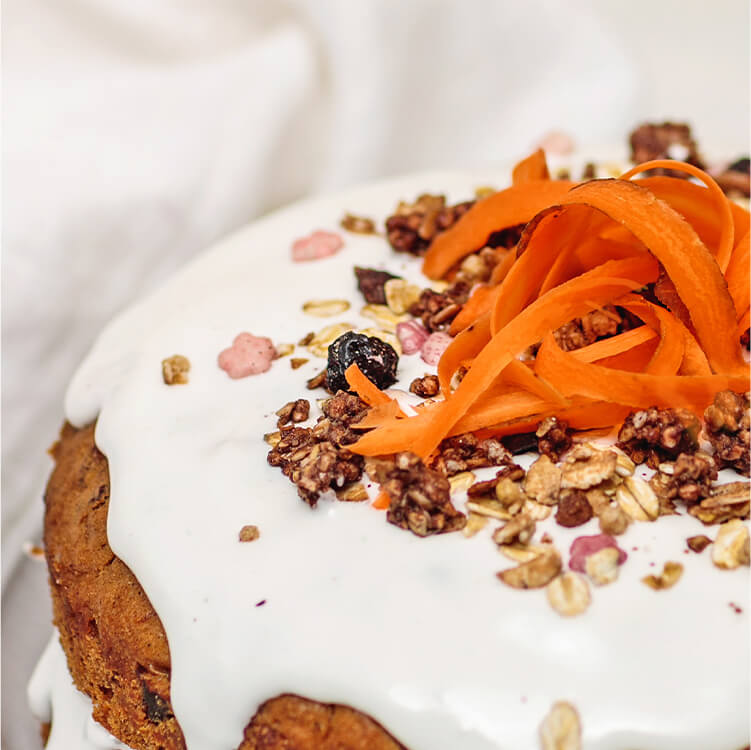 Naked Carrot Cake auf einem Teller, mit geraspelter Möhre dekoriert