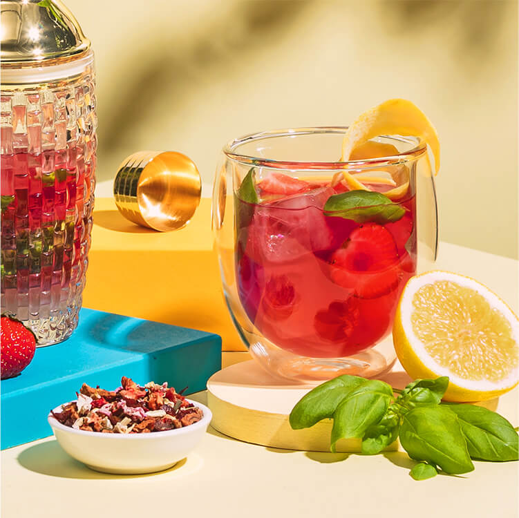 Strawberry Basil Smash im Glas und daneben Erdbeeren und eine halbe Zitrone