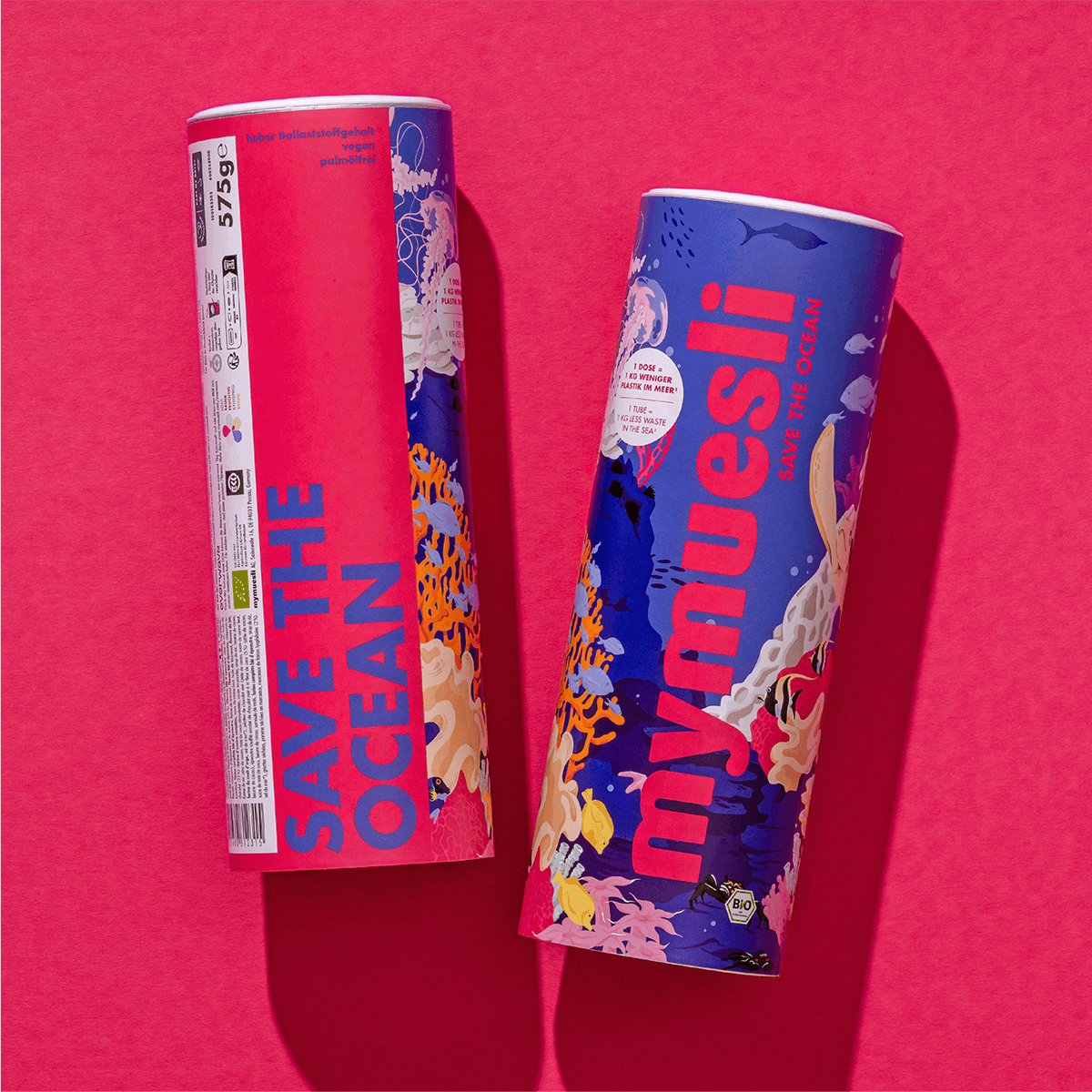 Zwei mymuesli -Dosen der Edition „Save the Ocean“ liegen nebeneinander auf einem pinkfarbenen Untergrund.