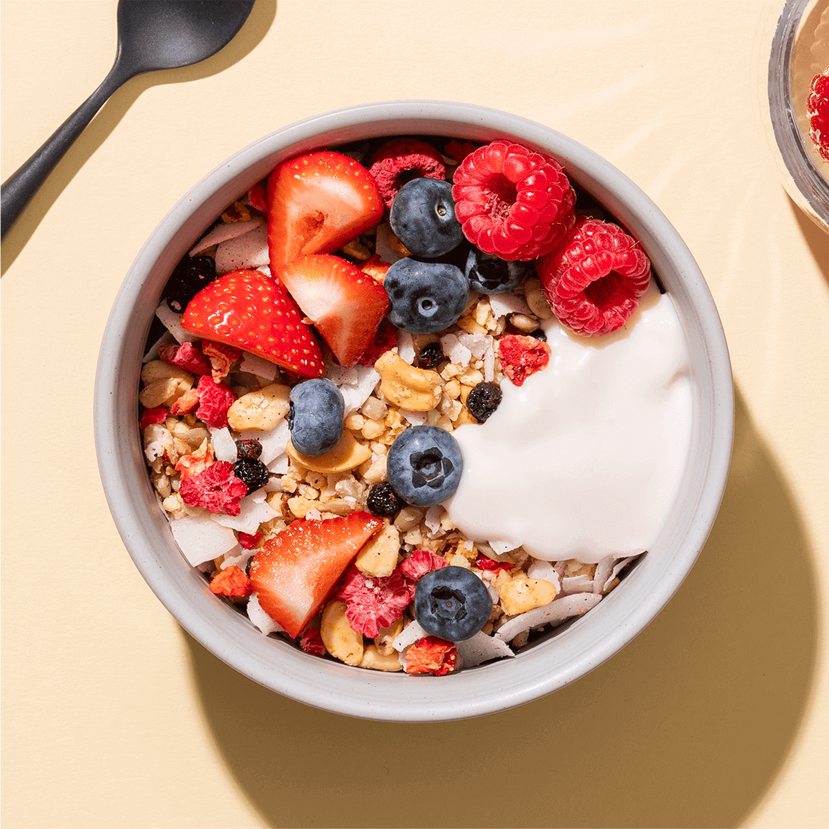 mymuesli Bio Paleo Coconut Nut Crunchy Müsli in Schale mit frischen Himbeeren, erdbeeren und Blaubeeren sowie Joghurt
