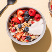 mymuesli Bio Paleo Coconut Nut Crunchy Müsli in Schale mit frischen Himbeeren, erdbeeren und Blaubeeren sowie Joghurt
