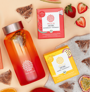 Tree of Tea Ice Tea Starter Set mit einer aufgefüllten Ice Tea bottle in Rosa. Drumherum liegen die enthaltenen Ice Tea Sorten mit frisch aufgeschnittenen Erdbeeren, Wassermelone, Mango und Passionsfrucht.