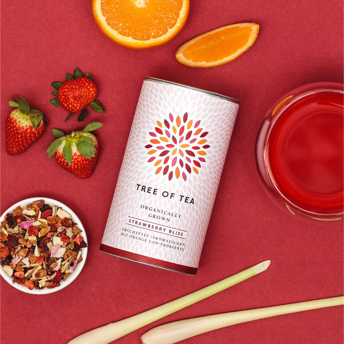 Tree of Tea Strawberry Bliss Früchtetee und daneben ein Glas Tee und Erdbeeren