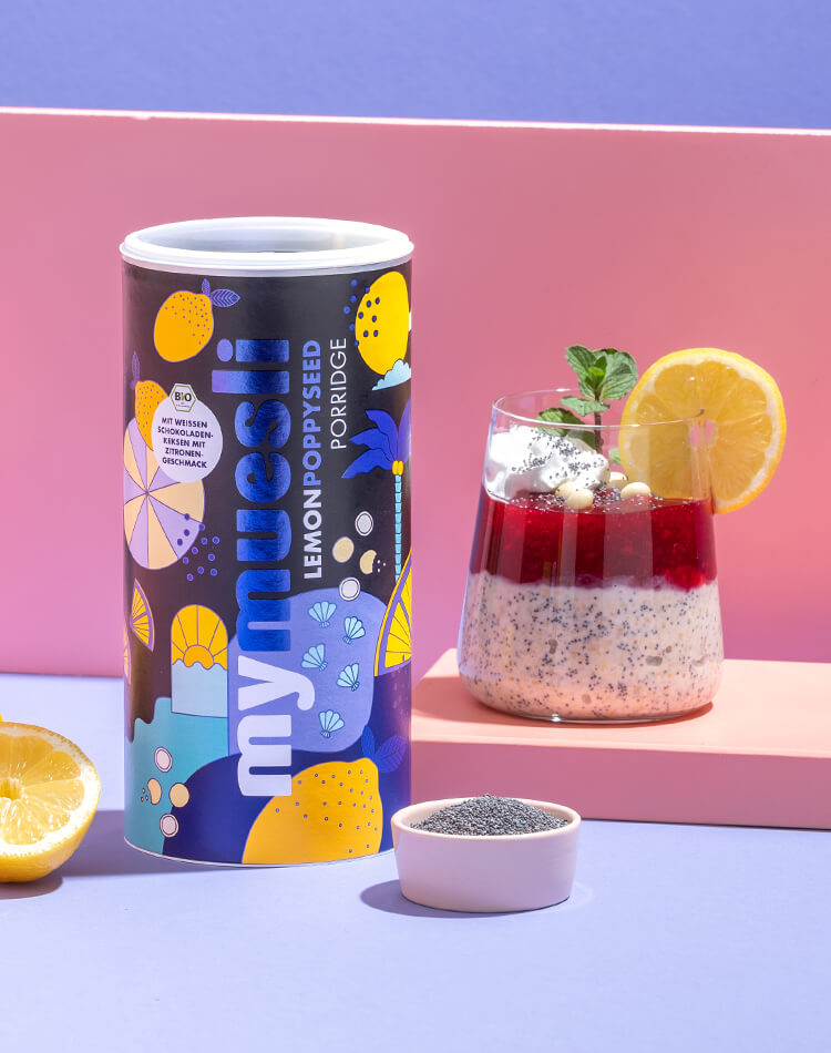 article3b-muesli-poppyseed-porridge.jpg Illustrierte Lemon Poppy Seed Porridge Dose neben Zitrone, Mohn und Glas mit Porridge Dessert